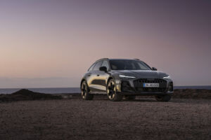 ¾ Front view of the Audi A6 allroad (plateau grey metallic) against a calm sea horizon at dusk.